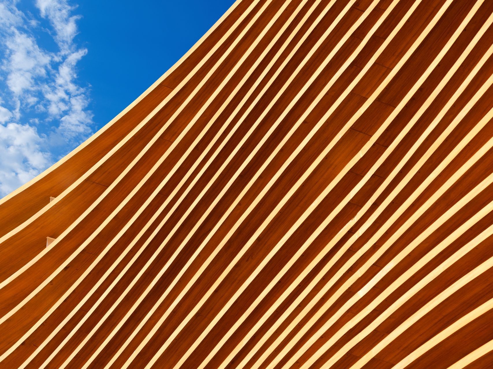 Närbild på moden träarkitektur mot en blå himmel med moln