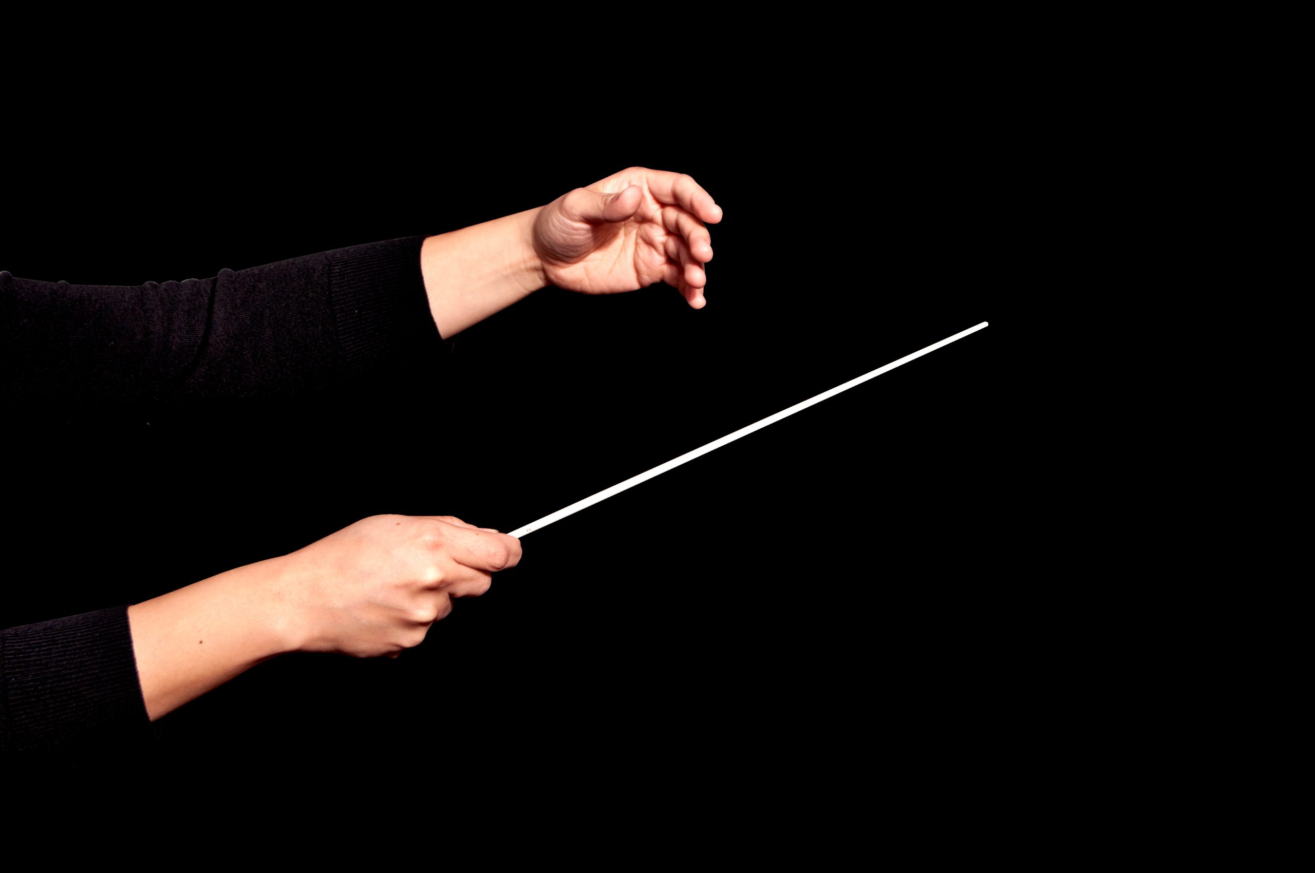 Kvinnlig dirigents händer mot en svart bakgrund.ck background