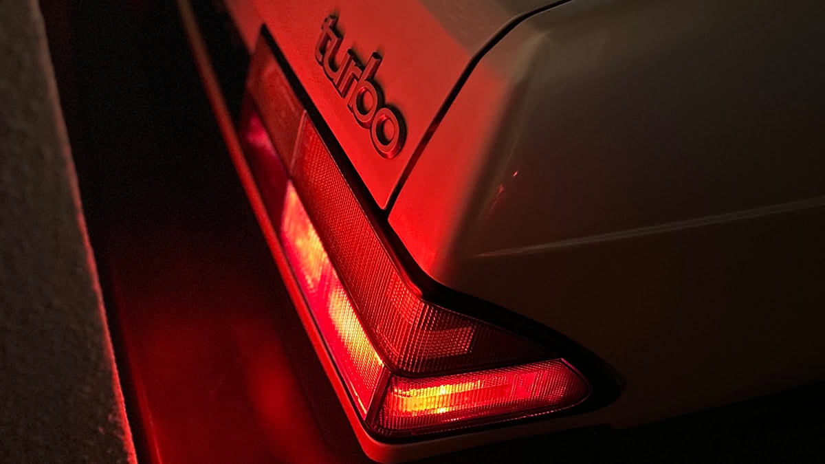 Röd belysning på en bils baklampa. En Saab- dekal skymtas.