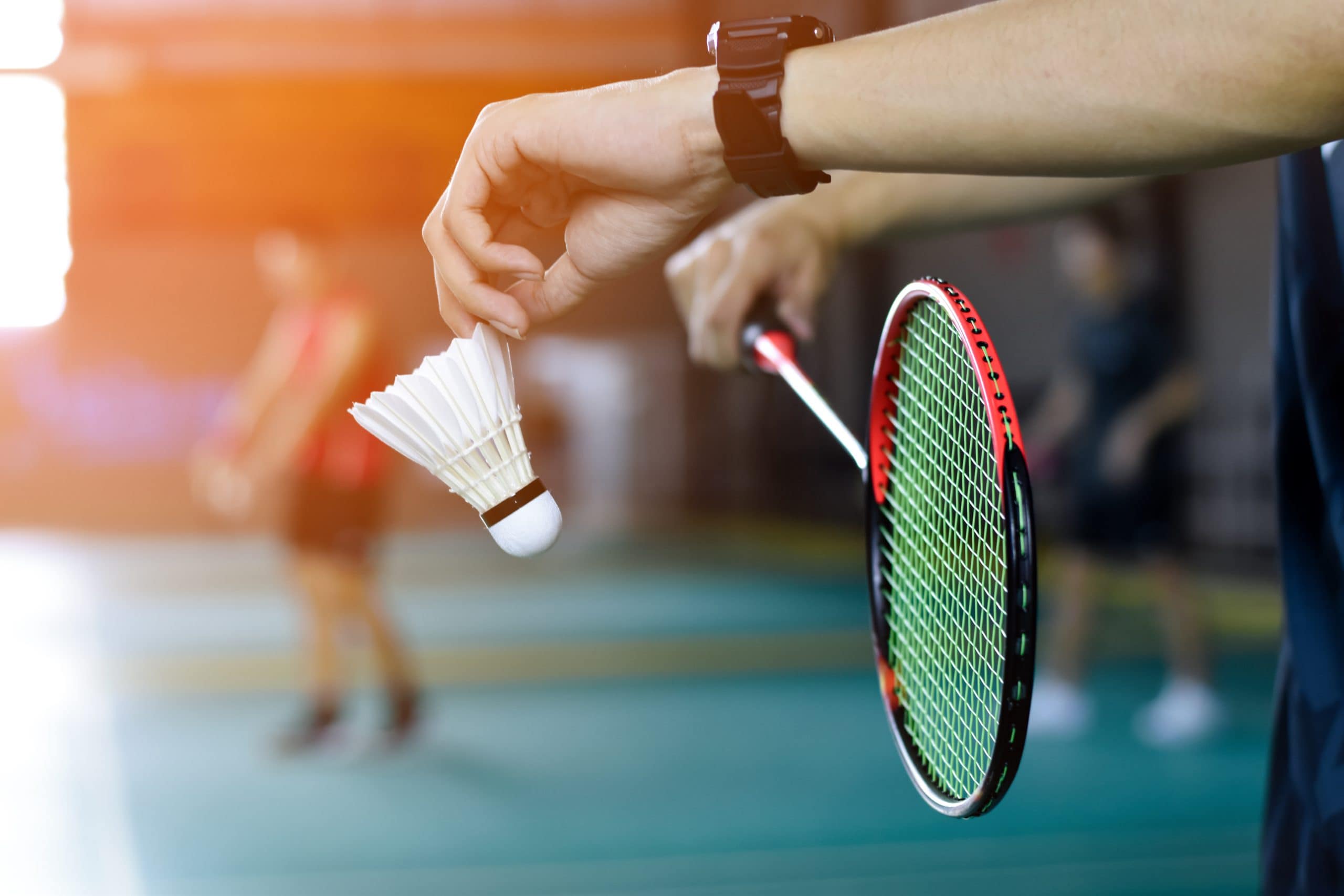Ett par händer som håller en badminton racket och ball.